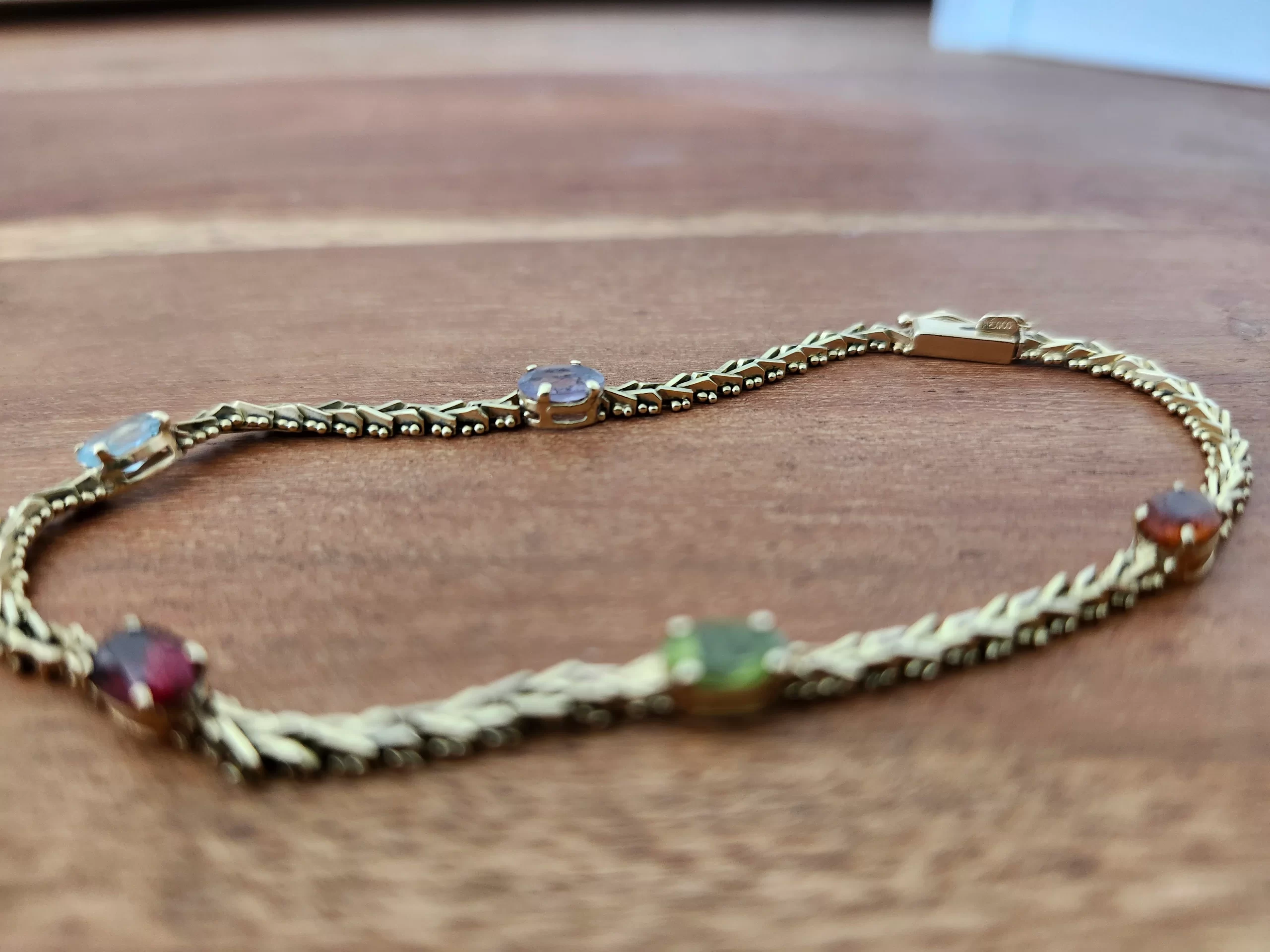 A 14 karat gold mexican gemstone bracelet on a table.